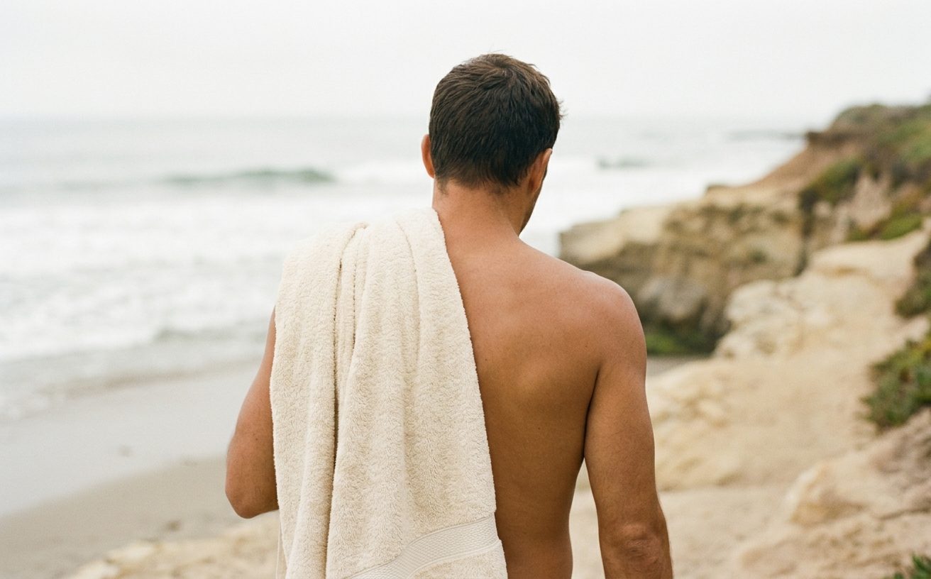 Man with a towel over his shoulder walking up a Santa Cruz beach